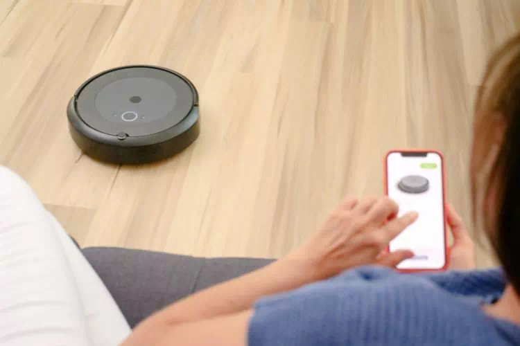 Femme programmant son robot aspirateur grâce à l'appli sur son téléphone portable