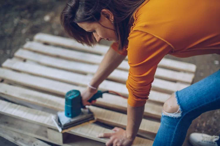 Femme ponçant une palette pour faire de la récupération