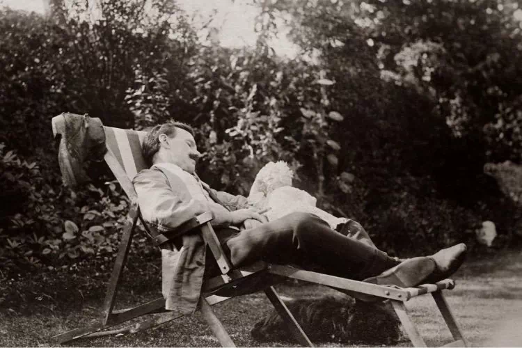 Homme se reposant dans un transat dans son jardin à l'abri des regards derrière une haie