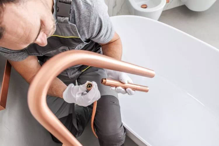 Plombier en train de refaire la tuyauterie dans une salle de bain