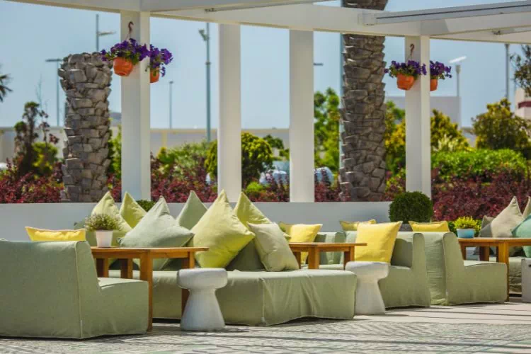 Terrasse d'un restaurant avec des banquettes agrémentées de coussins autour de tables