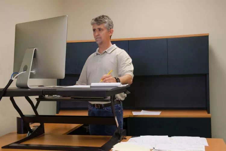 Homme travaillant debout sur son ordinateur posé sur une table surélevée