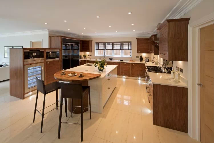 Grande cuisine ouverte avec un long plan de travail en L, des meubles bas, des meubles hauts et une large colonne