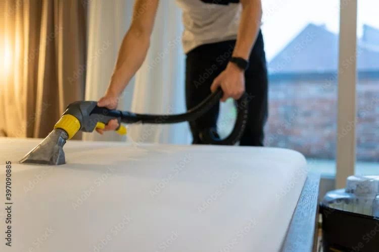 Femme nettoyant un matelas avec une shampouineuse