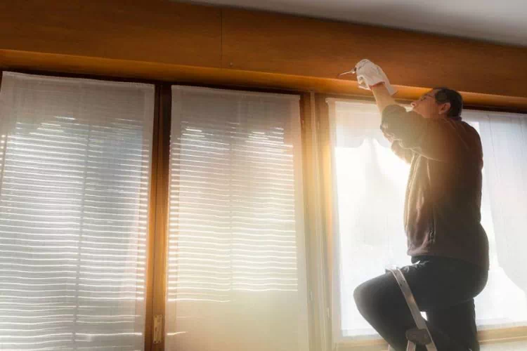 Homme sur une échelle réparant des volets
