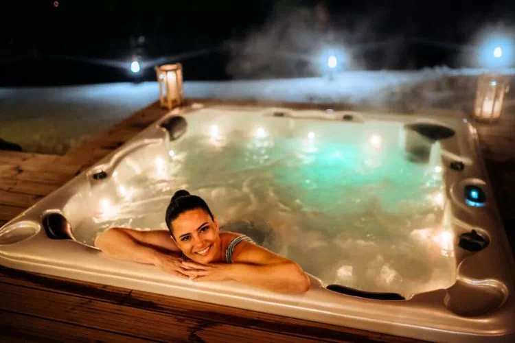 Jeune femme dans un spa en extérieur la nuit