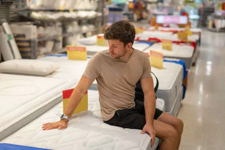 Homme essayant un matelas dans un magasin