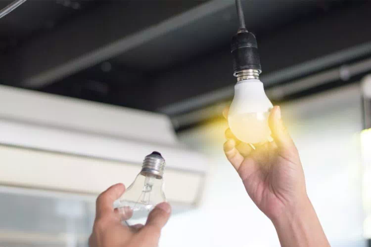 Personne remplaçant une ampoule à incandescence par une ampoule LED