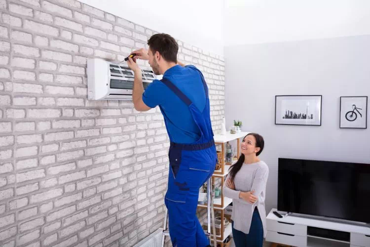 Technicien en train d'installer une climatisation dans un salon