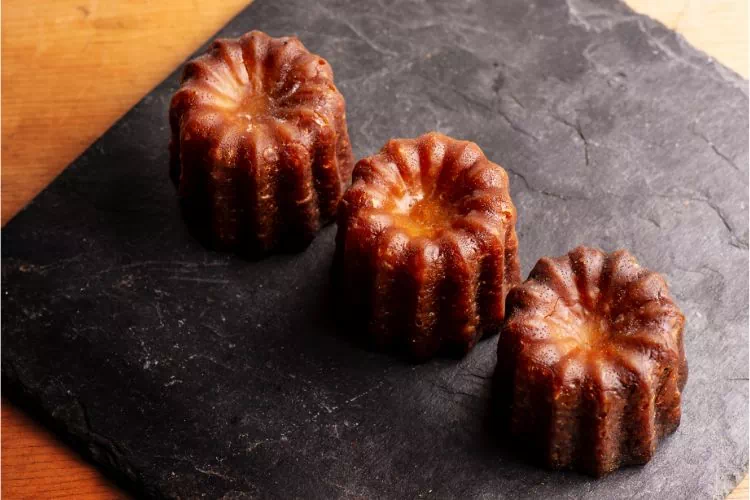Trois canelés sur une plaque d'ardoise