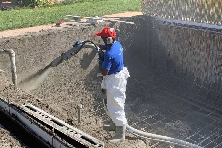 Ouvrier en train de projeter du béton pour la fabrication d'une piscine