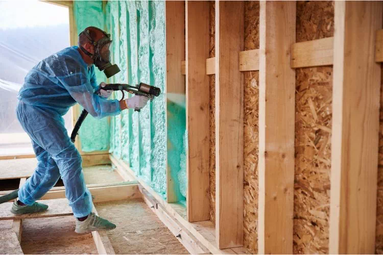 Ouvrier répandant du polyuréthane pour isoler des murs par l'intérieur