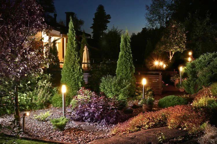 Luminaires illuminant un jardin devant une maison la nuit