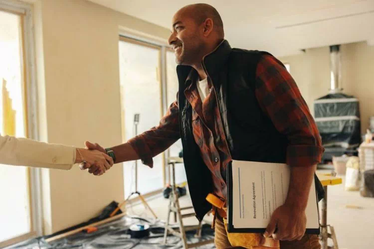 Entrepreneur sur un chantier de rénovation serrant la main de son client