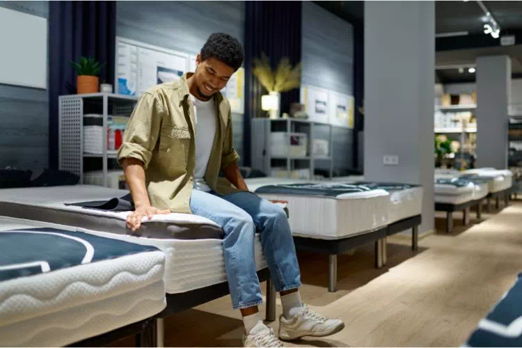 Jeune homme essayant des lits dans un magasin