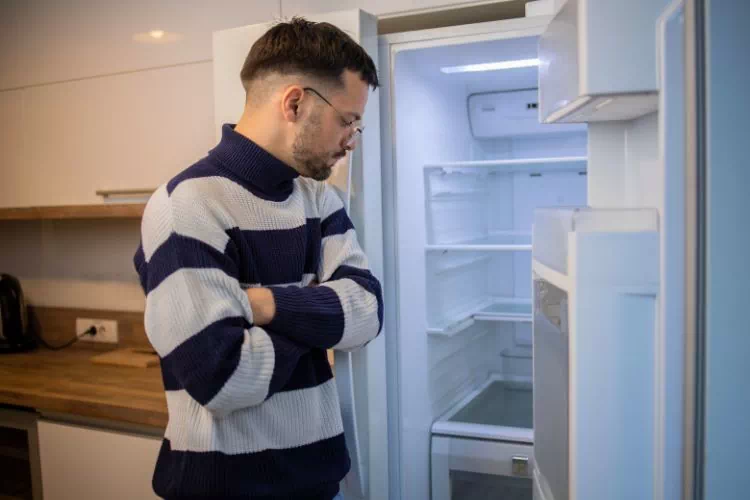 Homme devant un frigo vide