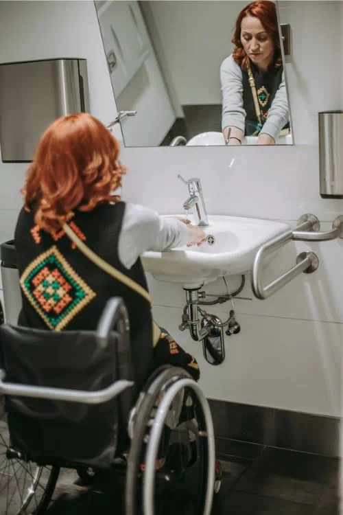 Femme handicapé en train de se laver les mains au lavabo