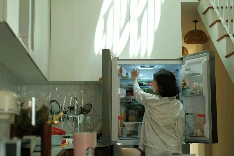 Femme en train de prendre un truc dans son frigo