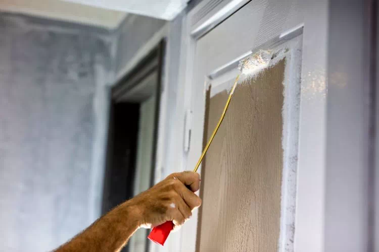 Homme en train de peindre une porte en deux couleurs